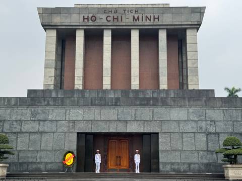       Mausoleum with guards outside on steps, set against an overcast sky.
  