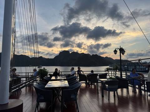       People seated on a boat during sunset with scenic hills.
  