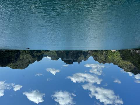       Scenic bay surrounded by lush green cliffs and blue water.
  