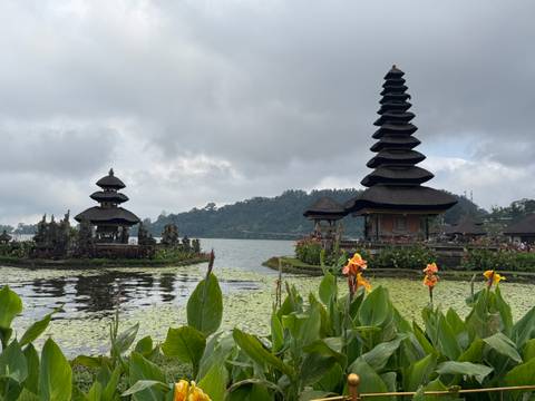       Water temple set on a lake with decorative flags and flowers.
  