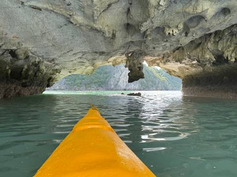       Kayak entering a cave with a scenic view of cliffs beyond.
  