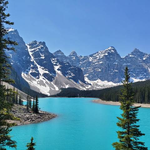 Stunning turquoise alpine lake surrounded by snow-capped mountains.