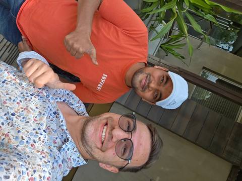 Two men giving thumbs up in front of a building entrance.