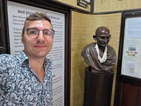 Man taking a selfie with a bust of a famous historical figure.