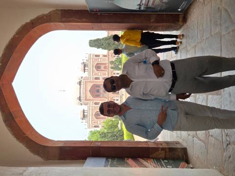 Two men posing in front of a historic mausoleum with gardens.