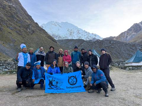      Group of trekkers posing with a snowy mountain backdrop.
  