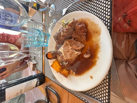 Plate with a traditional meat dish and wine glasses.