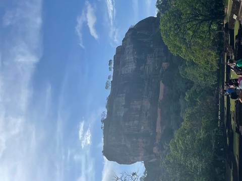 The Sigiriya Rock Fortress with visitors walking towards it.