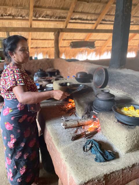 Woman cooking traditional food on a clay stove with fire.
