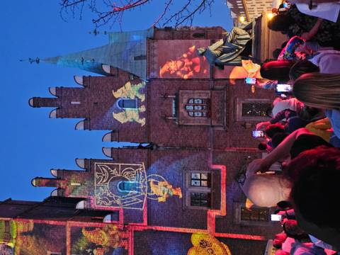 People in front of a brick building with projections on it.