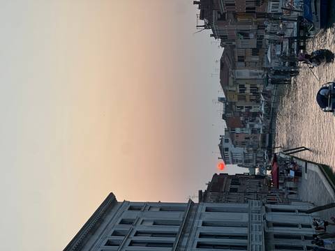       Venetian canal at sunset with boats.
  