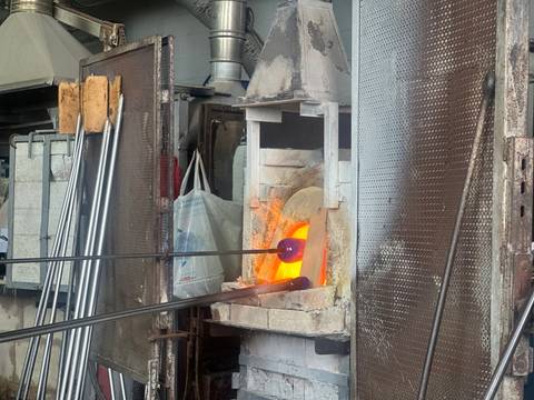       Glassblowing in progress in a workshop.
  