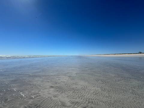 Expansive sandy beach with a clear sky.