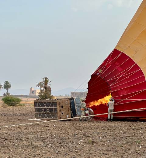 People inflating a hot air balloon with a flame.