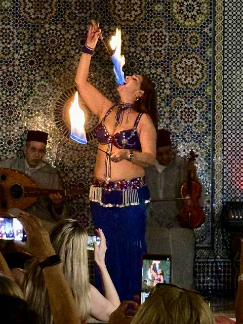 A woman performing a traditional dance with musicians in the background.