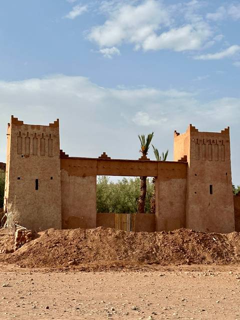 Traditional Moroccan gateway with palm trees in the background.