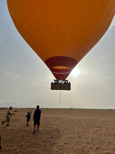       A hot air balloon in the sky with passengers visible in the basket.
  