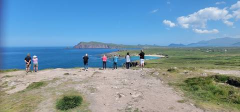       People observing a coastal landscape from a high vantage point.
  