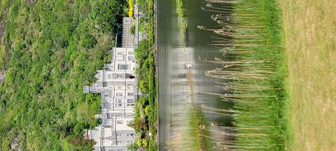       A castle by a lake with a mountainous backdrop.
  