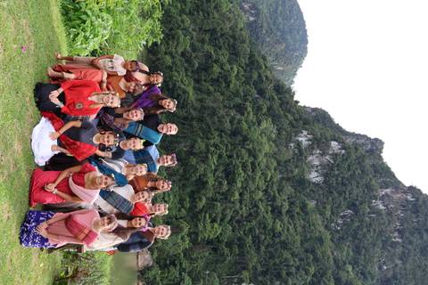 A group of people posing in traditional attire against a mountainous backdrop.