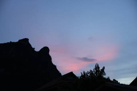 Silhouette of a mountain against a sky tinged with pink and blue hues.