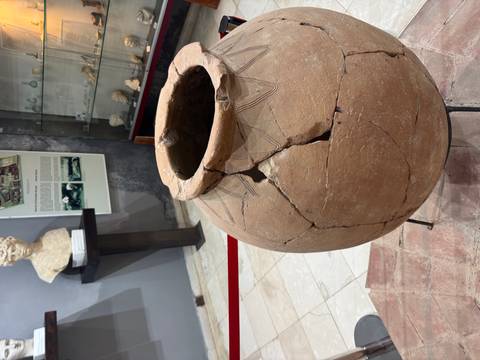 Ancient clay pot in a museum setting with informational displays in the background.
