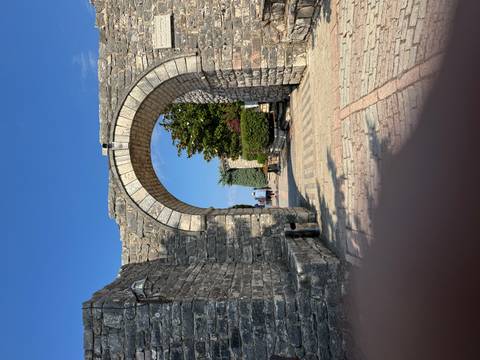 Stone archway leading to a courtyard with people walking through.