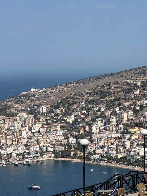 Aerial view of a coastal city with hills and ocean in the background.