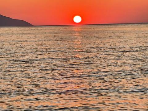 Red sunset over the ocean with a silhouette of land.