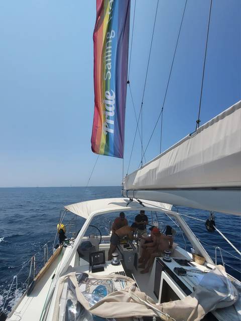 Sailboat with a pride flag sailing in open waters.