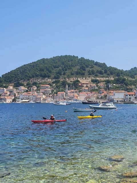 Kayakers enjoying a coastal landscape with a village in the background.