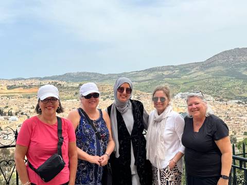 Group of tourists with a scenic city and mountains in the background.