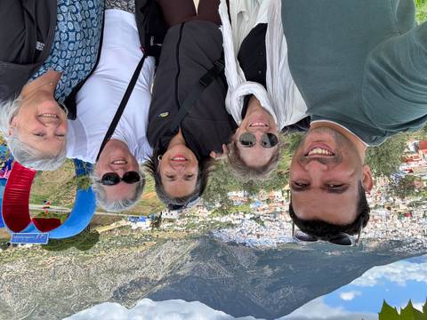 Smiling group with a city view and heart-shaped monument behind.
