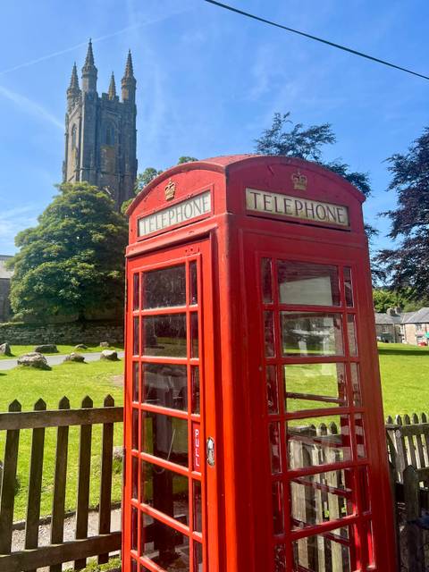 Traditional British red telephone box in a grassy area.
