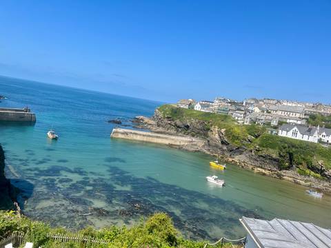 Coastal town with boats docked in clear water and rocky shore.