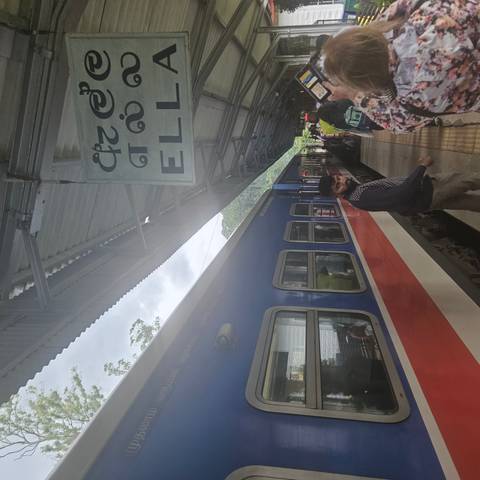 Train station platform with a colorful train and people boarding.