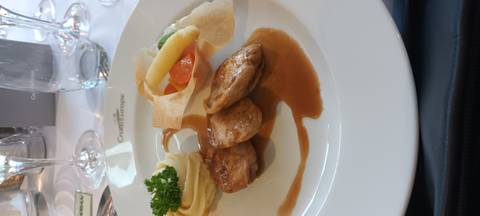 Plated meat dish with vegetables and sauce.