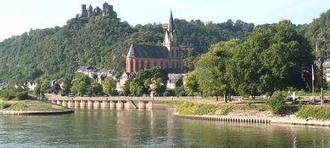 A picturesque landscape with a church and castle on a hill by the river.