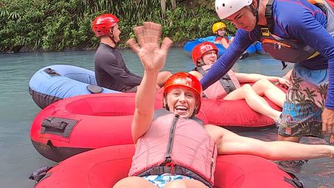 Group of people enjoying a river tubing adventure with lush greenery around.