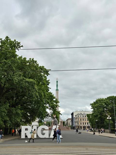 A monument with a star atop surrounded by trees and a cloudy sky.