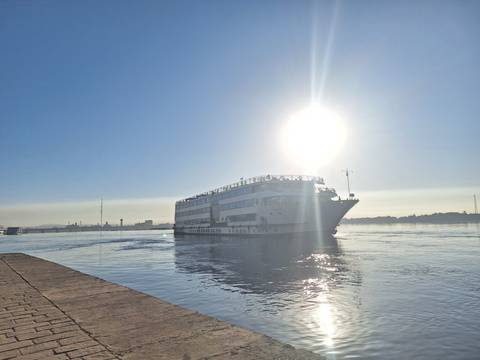 A river with a cruise ship under the bright sun.