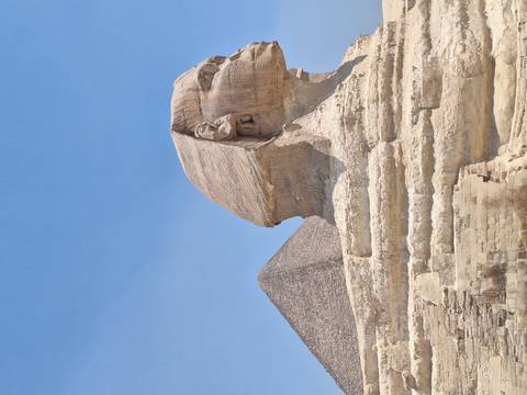       The Great Sphinx of Giza with a pyramid in the background.
  