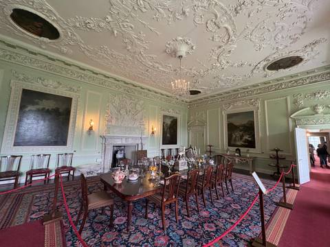 An ornate dining room with detailed ceiling and classic furniture.