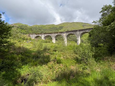 A scenic green landscape featuring a tall viaduct.