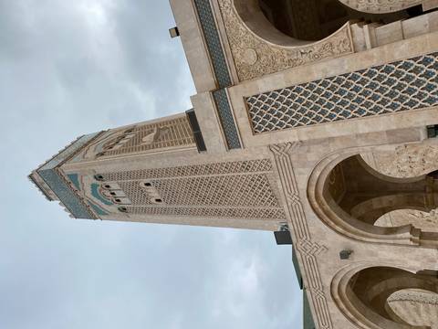 A tall minaret with intricate details on a cloudy day.