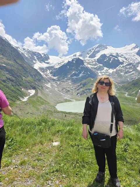 A woman posing in a mountainous area with a glacier in the background.