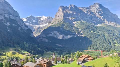       Stunning landscape of mountains, a church, and a village in a valley.
  