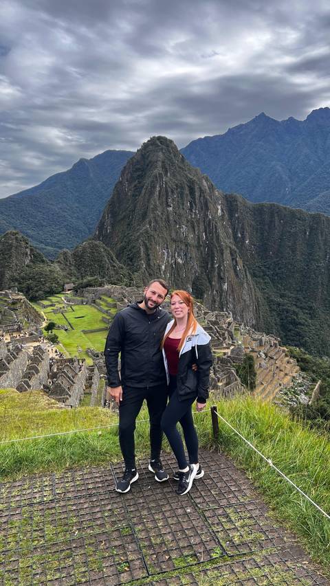 Couple posing at Machu Picchu with iconic ruins and mountains.