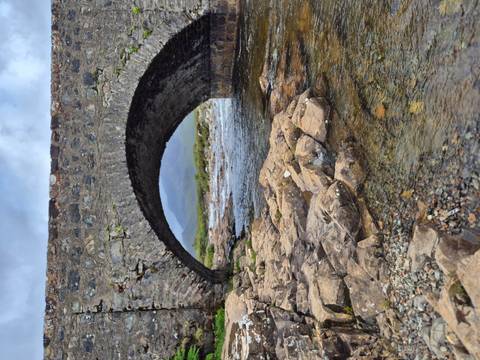 Stone bridge over a river with rocky surroundings.