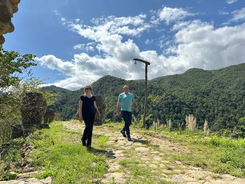 Two people walking on a mountain path with scenic views.